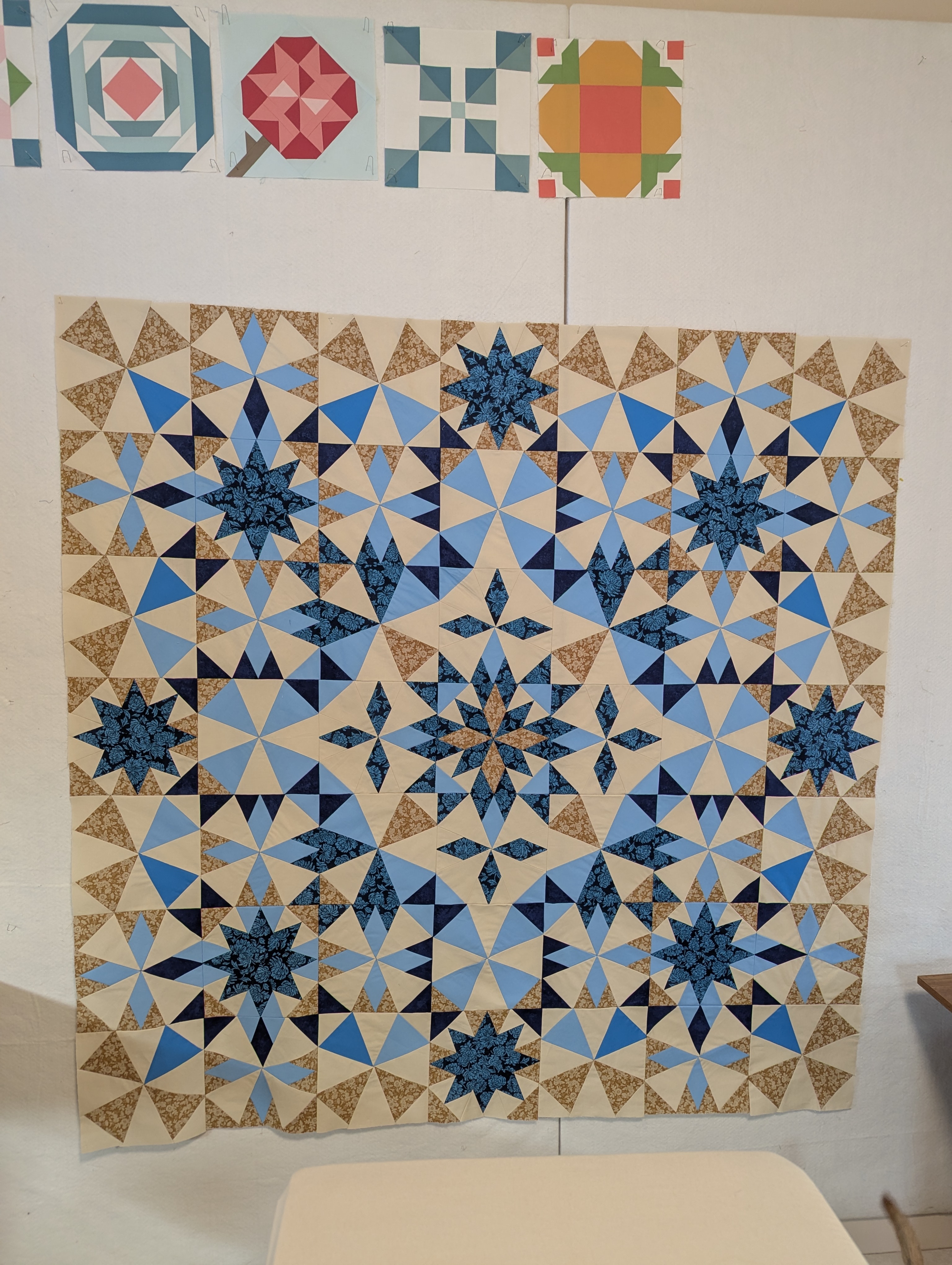 A blue and tan star quilt in the Alaska pattern, pinned to a design wall.